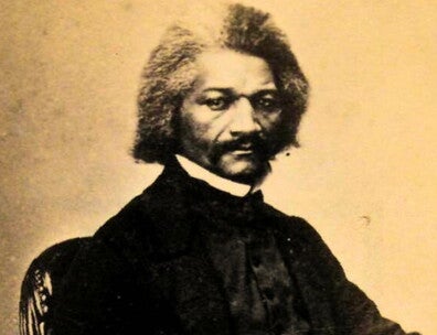 Image of man sitting and posing for a black and white photograph.