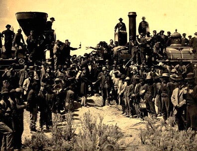 The photograph shows the celebration of the eastern and western sections of the transcontinental railroad being connected with a golden spike at Promontory Summit, Utah, on May 10, 1869. 