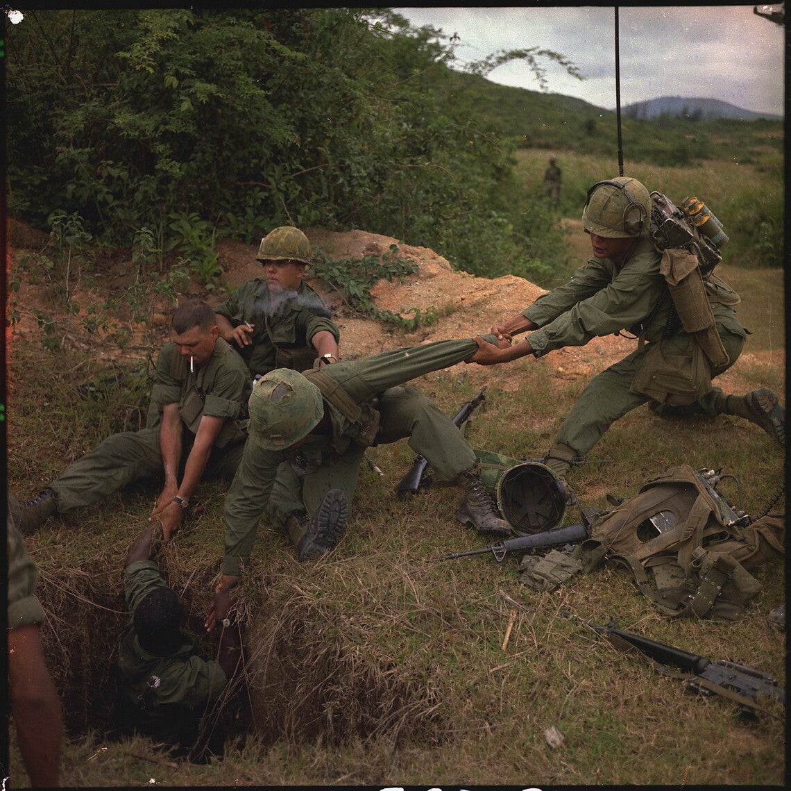 An infantryman is lowered into a tunnel by members of the reconnaissance platoon.