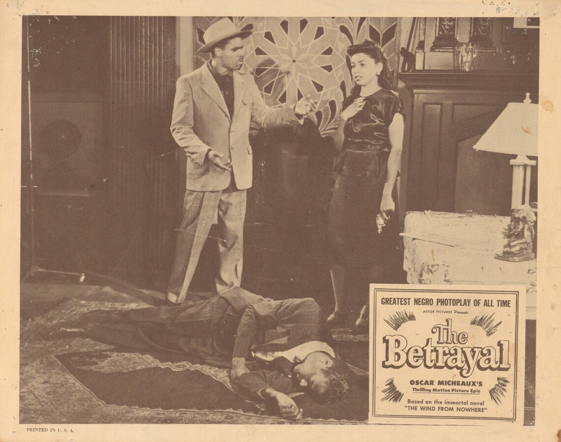 A lobby card for the movie "The Betrayal". The card is comprised of a black-and-white image of a man and woman standing in a room in front of another man lying on the carpet on the floor. The man on the floor appears to be dead. The woman is wearing a dark shiny dress and is holding a gun at her side in her left hand. Her right hand is resting on her chest and her face appears to be in a state of shock. The man standing next to her is wearing a light colored suit and hat and is extending his hand toward her