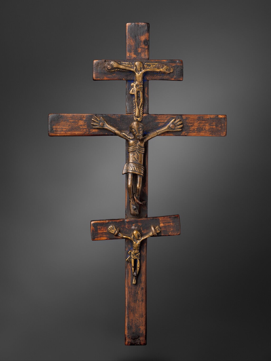 A crucifix sculpture with three crosses, each with a skeletal Christlike figure crucified.