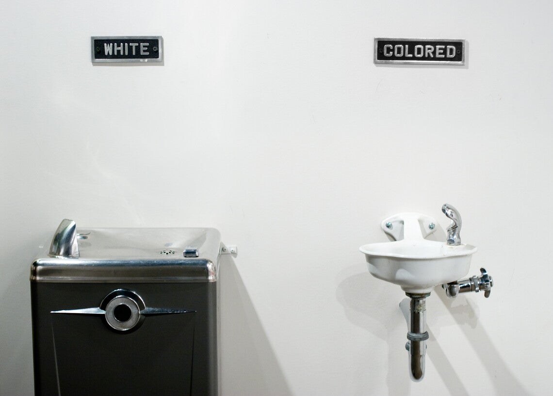Two water fountains: at left, a larger water fountain labeled "white" and a smaller fountain labeled "colored." The labels appear above the fountains.