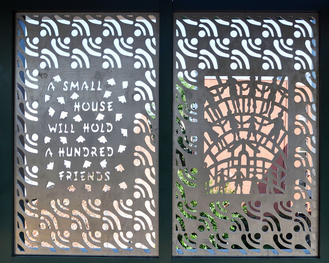 A color photograph of two panels of perforated metal, buildings and the sky visible through the perforations
