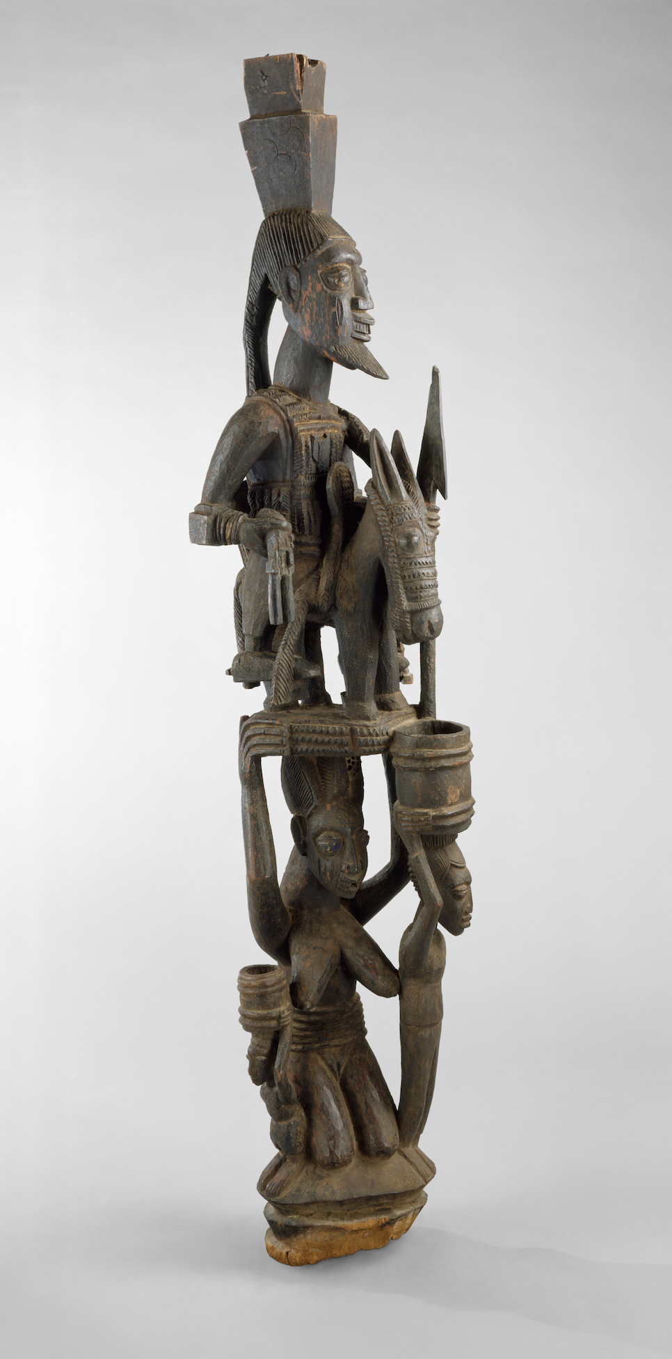 A stylized post of (from top to bottom) a bearded man atop a horse, held up by a woman.