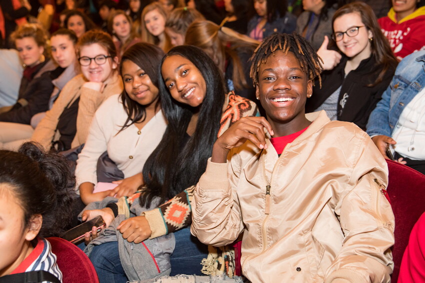 A group of students smile for a photo while attending a performance of Hamilton the musical.